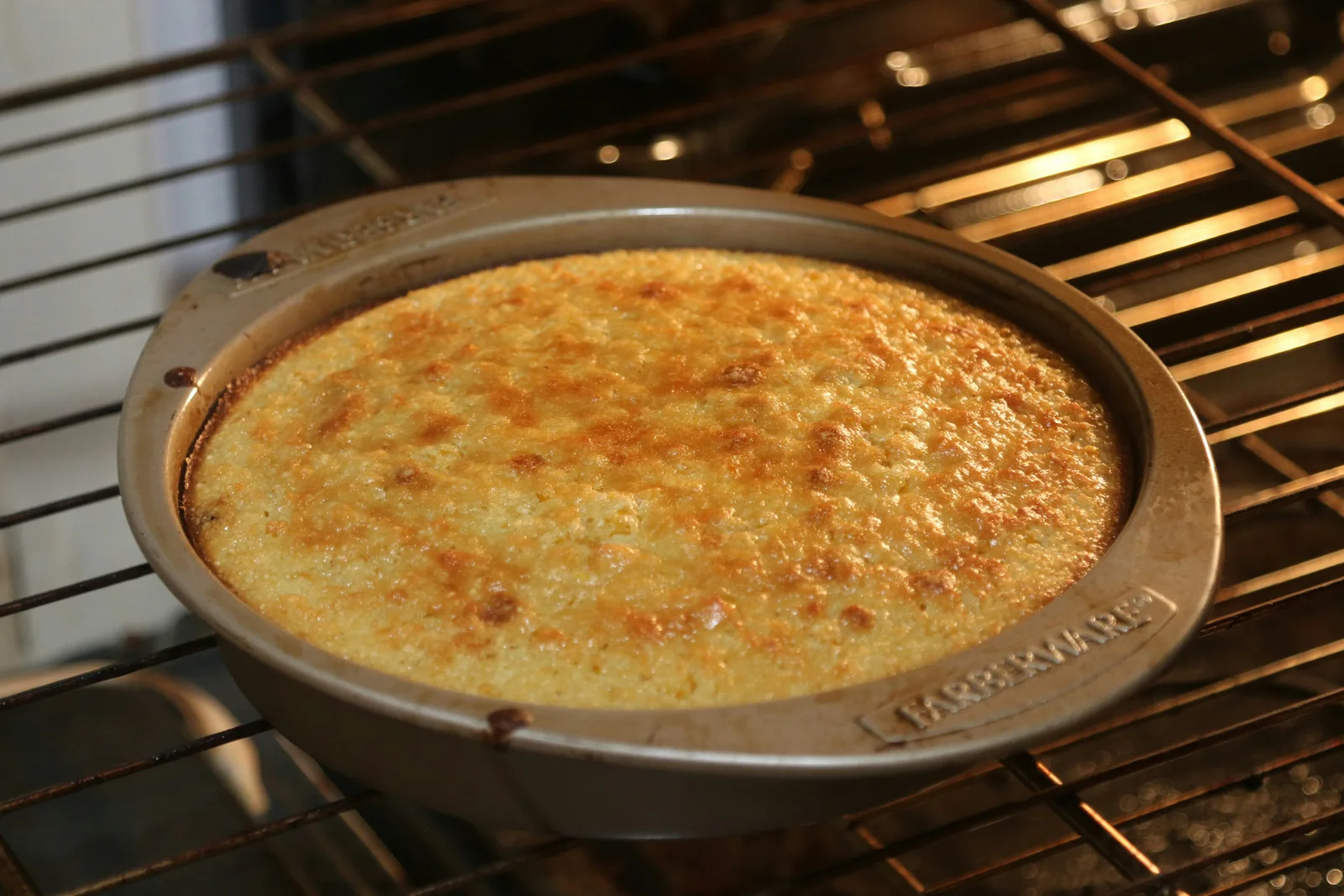 Golden cornbread in a round baking pan inside an oven