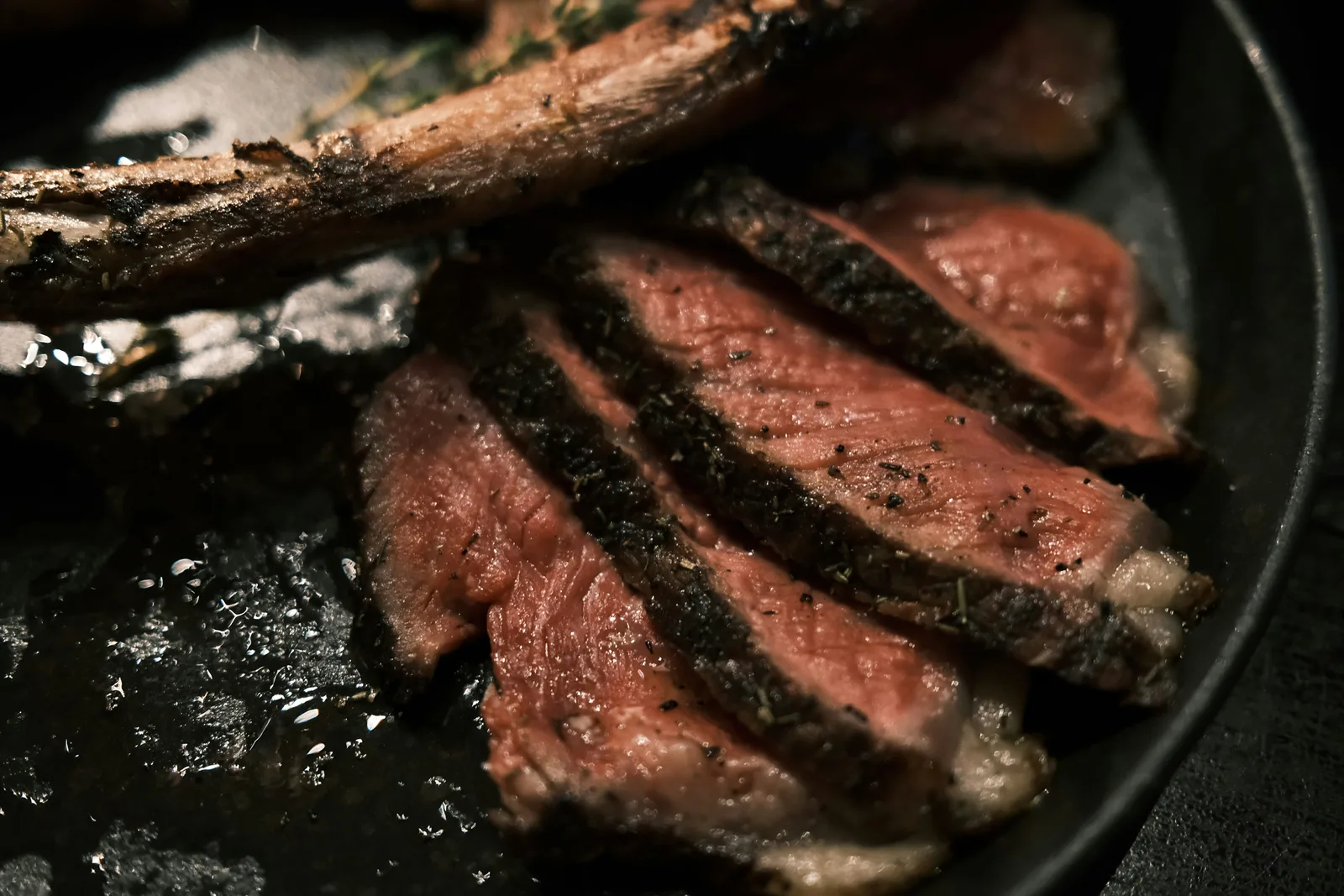 Sliced medium-rare steak with a dark seared crust in a black pan